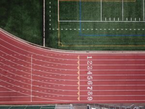 Aerial perspective of a red running track and adjacent green field.