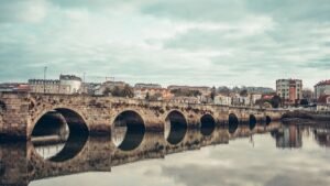 Scenic view of a historic stone bridge with reflections in Burgo, Spain.