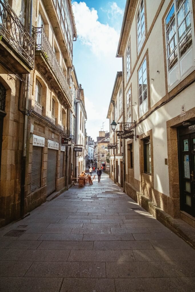 Scenic view of a narrow street in Santiago de Compostela, capturing its historic architecture and bustling activity.