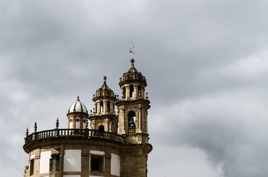 Gothic church towers under a cloudy sky in Pontevedra, Spain. Capturing architectural beauty.