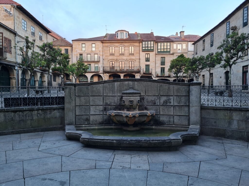 Charming old European square with a central fountain and historic buildings.