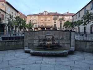 Charming old European square with a central fountain and historic buildings.